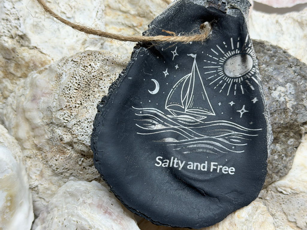 Decorative stone with sailboat design and 'Salty and Free' text on a rocky background