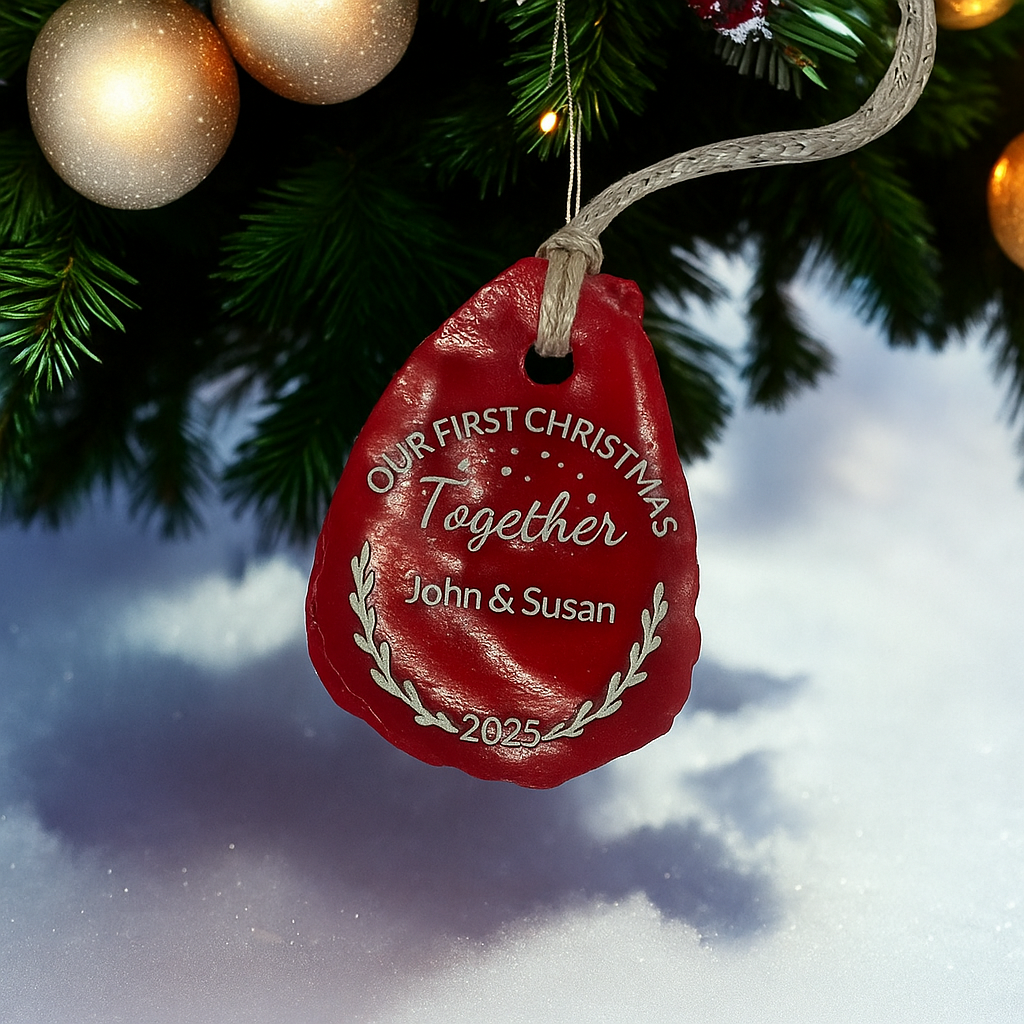 Red Christmas ornament with 'Our First Christmas Together' text, hanging on a tree with snow and lights in the background.